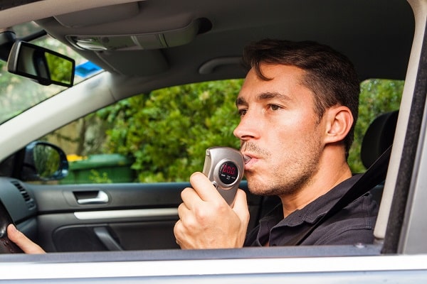 Man in car blowing into breathalyzer